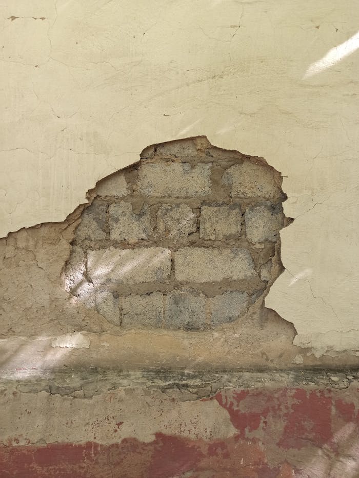 Weathered wall showing exposed bricks and peeling plaster, creating an antique texture.